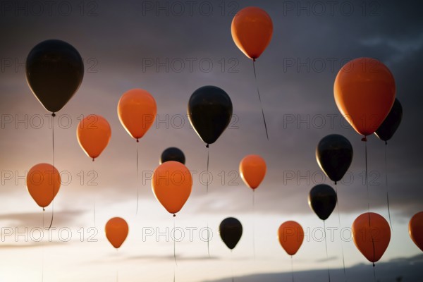 Round orange and black Halloween balloons floating in the sky, festive autumn decoration. Generative ai, AI generated