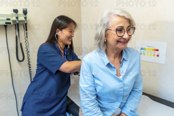 Female doctor using stethoscope checking heartbeat and breathing of senior patient during medical consultation in hospital room