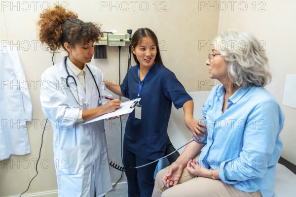 Medical professionals taking care of elderly woman's health, performing blood pressure check during medical examination in clinic
