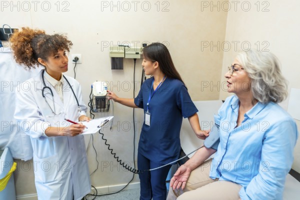 Medical professionals taking care of elderly woman's health, performing blood pressure check in hospital room