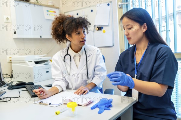 Doctor explaining medical procedure to a nurse wearing gloves, sitting at a desk in a hospital office
