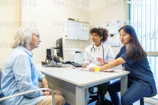 Doctor and nurse discussing medical results with elderly woman during consultation in clinic office