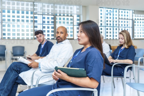 Diverse group of healthcare professionals participating in a medical conference, actively engaging in discussions and taking notes