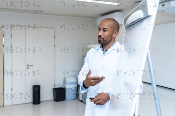 Confident male doctor explaining something using a whiteboard during a medical presentation in a hospital or clinic