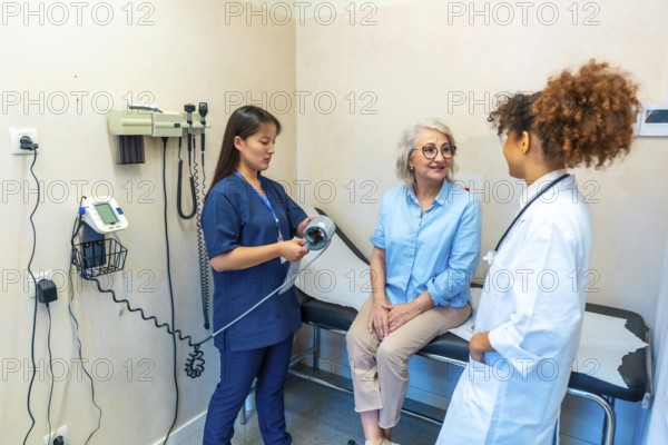 Medical professionals attending a senior woman during a medical checkup, preparing to measure her blood pressure
