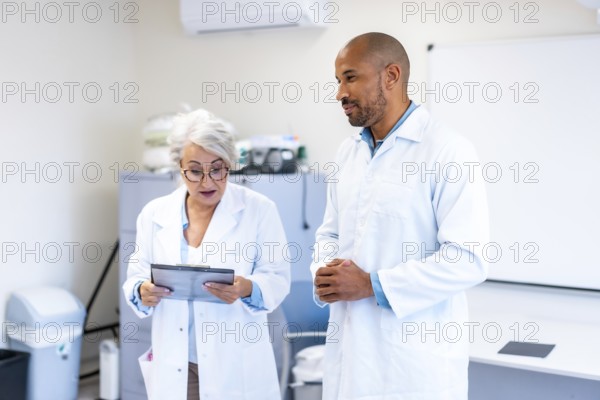 Two doctors engaged in a discussion over a patient chart inside a hospital room, collaborating on diagnosis and treatment strategies