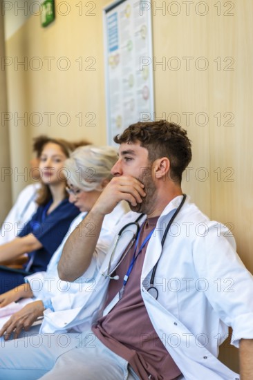 Group of medical professionals sitting in a hospital hallway, feeling exhausted after a long shift