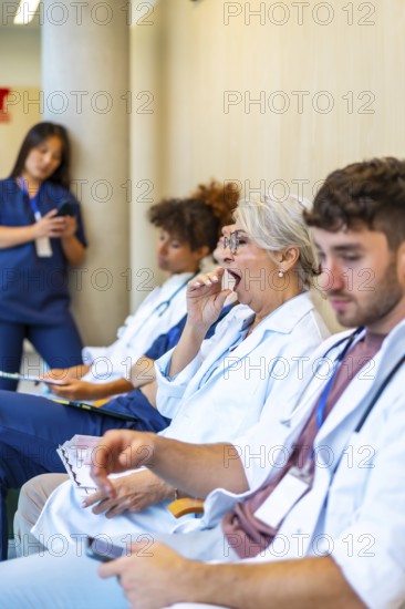Exhausted doctors and nurses yawning and sitting in a hospital corridor, waiting for patients after enduring a long and demanding shift
