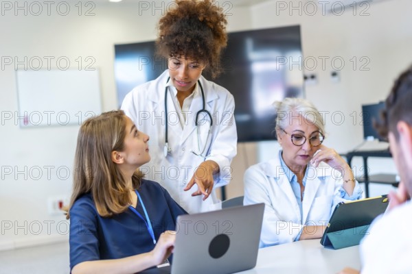 Doctors and nurses collaborating on patient care, analyzing medical data on laptop and tablet, improving healthcare strategies