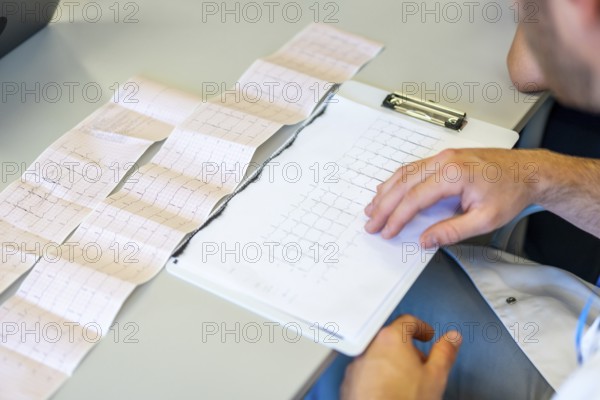 Doctor examining electrocardiogram printout, focusing on heart health and medical diagnosis in healthcare setting