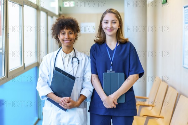 Doctor and nurse smiling while holding medical records in a hospital corridor, showcasing teamwork and professionalism in healthcare