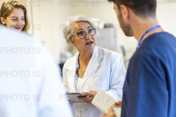 Senior female doctor briefing medical staff during a hospital meeting, discussing patient care strategies and sharing her expertise with the team