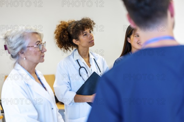 Doctors and nurses engaging in a medical staff meeting, attentively listening to a speaker while discussing important healthcare topics