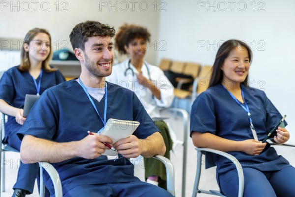 Group of smiling medical students attending a conference, taking notes and listening to the speaker in university lecture hall