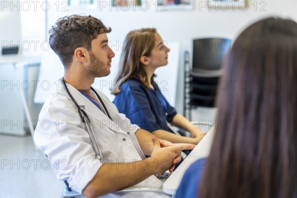 Medical professionals attending a conference in a hospital meeting room, listening to a presentation and learning new skills
