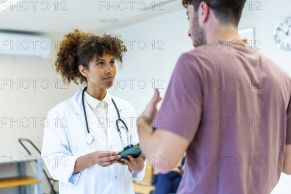 Doctor holding a tablet and listening to a patient explaining his symptoms in the waiting room of a hospital or clinic