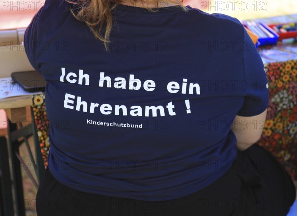 Overweight woman wearing a blue T-shirt with the inscription Ich habe ein Ehrenamt, Kinderschutzbund, Ehrenamtliches Engagement
