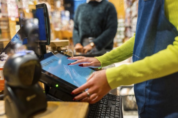 Salesperson using a touch screen cash register in an organic supermarket, selling natural and gluten free products