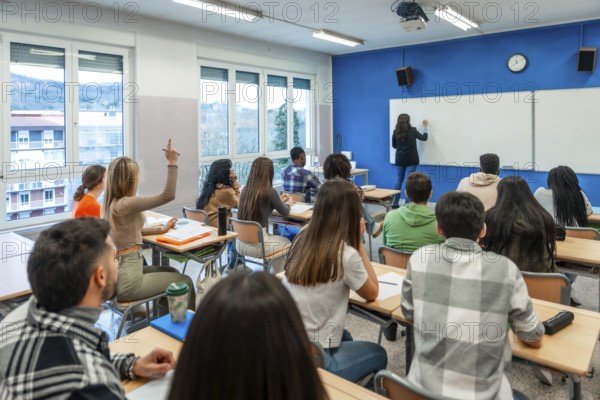 Multi ethnic university students listening to their teacher and raising their hand to answer a question in a classroom