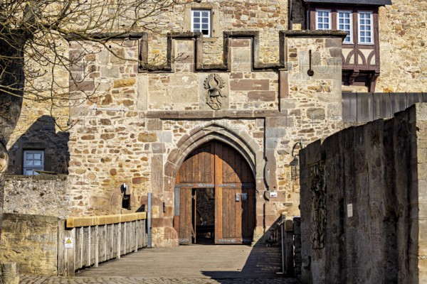 Medieval castle gate with stone walls and a heraldic coat of arms above it, The gate of Spangenberg Castle