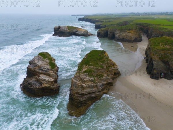 Gigantic, jagged rocks jutting out of the sea and lapped by foaming water, aerial view, Praia das Catedrais, Playa de las Catedrales, As Catedrais beach, Cantabrian Sea, Ribadeo, Galicia, Galicia, Spain