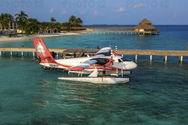 Seaplane floating in lagoon is moored at pier jetty of Maldives island Filaidhoo Reethi Faru, Raa Atoll, Maldives