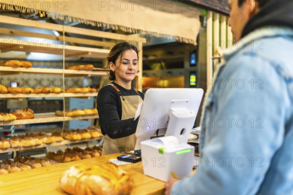 Rear view of a latin young man checking out in an artisan bakery attended by a latin young saleswoman