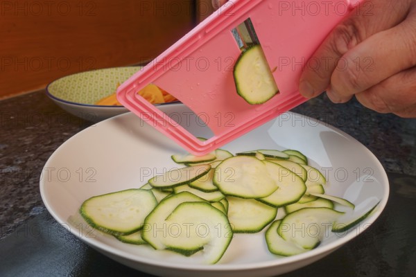 Swabian cuisine, preparing courgettes for mini dinettes, slicing vegetables, vegetable slicer, healthy, vegetarian, typical Swabian reinterpreted, man's hand, plate, traditional cuisine, food photography, studio, Germany