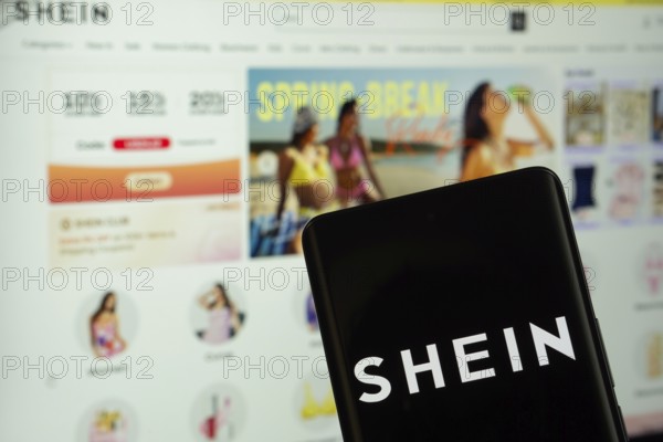 Dhaka, Bangladesh - 18 March 2025: The logo of the shein is displayed on a smartphone screen, and the website shein is visible on a computer screen in the background