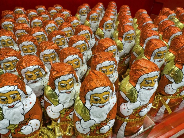 Display on the shelf of chocolate Santa Claus chocolate Santa Claus Santa Claus Santa Claus Santa Claus chocolate Santa Claus chocolate Santa Claus chocolate lice Santa Claus chocolate lice Santa Claus in color red of red staniol paper made of chocolate arranged like army of Santa Claus, Germany