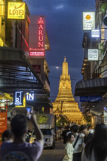 Wat Arun, Temple of Dawn at sunset with dark clouds. Boats on the Chao Phraya river. Tourist attraction in Bangkok, Thailand