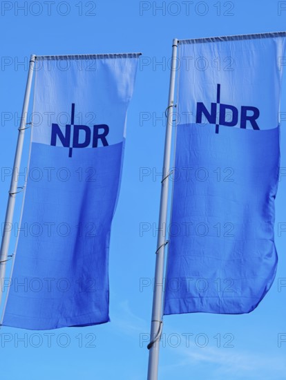 Two flags with lettering NDR, Norddeutscher Rundfunk, flagpoles, colours blue white, light wind, background blue, old town, Kiel, Schleswig-Holstein, Germany