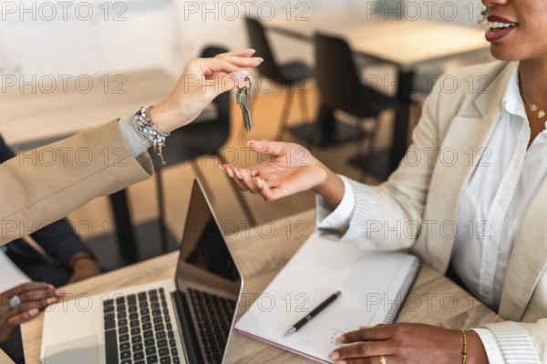 Businesswomen exchanging house keys after successful deal signing a contract in the office