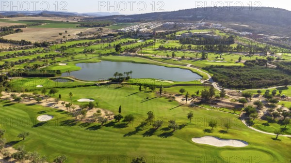 Wide aerial view of a luxury golf course with green grass and a lake