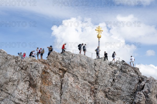 Many tourists at the summit of the Zugspitze with golden summit cross, overtourism, Wetterstein range, Bavaria, Germany
