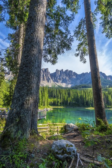 Stunning landscape showing turquoise water of lake carezza with the dolomites in the background on a beautiful summer day