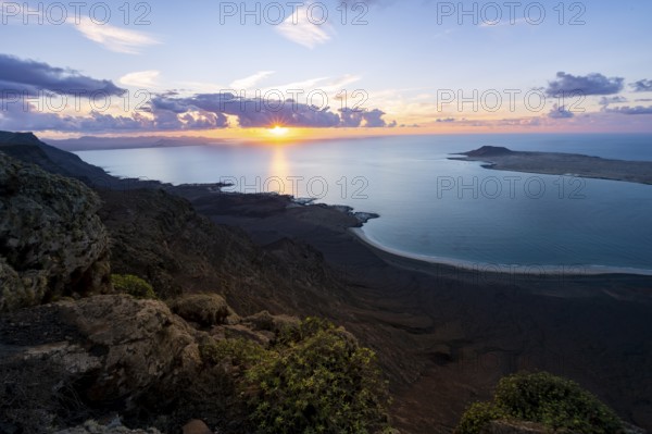 View from steep cliffs to sea and coast with sun stars, Mirador del Porrito viewpoint at sunset, Lanzarote, Canary Islands, Spain