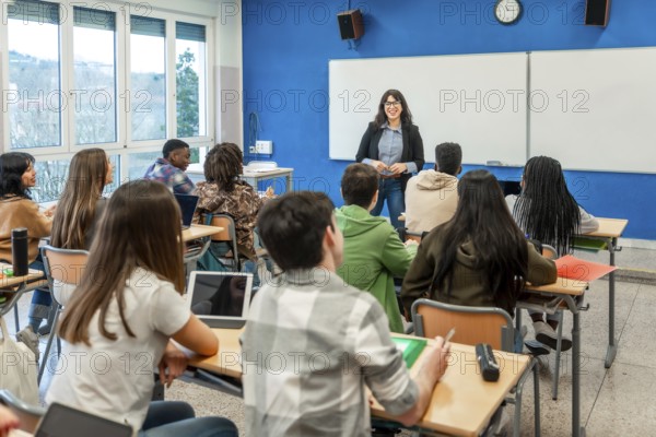 Female teacher explaining lesson to attentive multi ethnic high school students sitting at desks