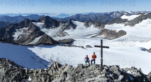 Panorama at the summit of the Wilder Freiger with summit cross and with glacier Übeltalferner and Wilder Freiger Ferner, two mountaineers at the summit in front of a spectacular mountain landscape, aerial view, Stubai Alps, South Tyrol, Italy