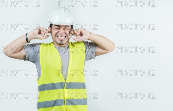 Young engineer covering ears isolated. Male Engineer man with ear pain