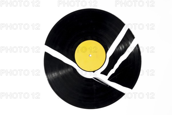 A black record with a yellow label that is broken into several pieces