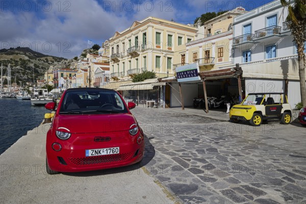 Red car on a promenade in a coastal town with Mediterranean architecture, Symi Town, Symi, Dodecanese, Greek Islands, Greece