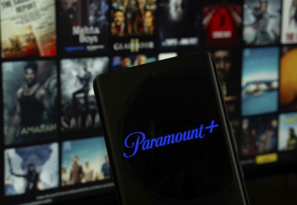 Dhaka, Bangladesh - 17 March 2025: The logo of the paramount+ is displayed on a smartphone screen, and the website paramount+ is visible on a computer screen in the background