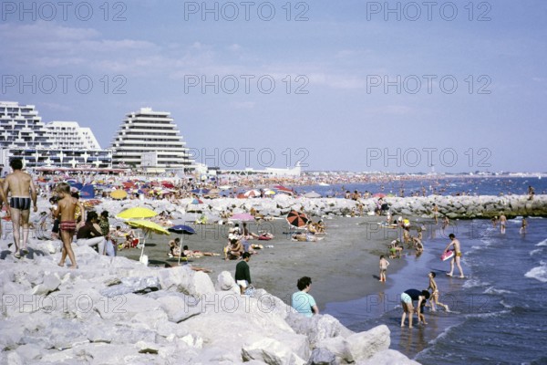 Crowded beach with modern pyramid-shaped hotels, La Grande Motte, Herault, France 1972