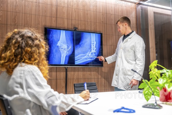 Doctors looking at x-ray scans of a hip in a traumatology meeting room