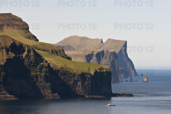 Fishing boat in front of Eysturoy, the basalt columns Risin and Kellingin at the back, Kalsoy, Faroe Islands, Denmark