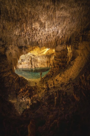 Beautiful view of stalactites and stalagmites surrounding lake martel in caves of drach, mallorca, spain