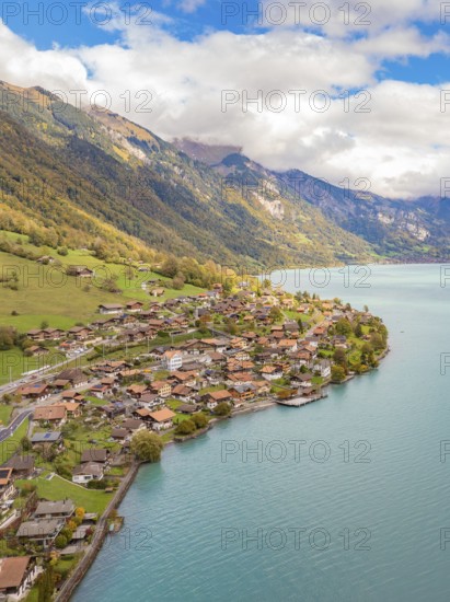 Alpine village on a lake with meadows and autumn colours, framed by mountains, Lake Brienz. Switzerland