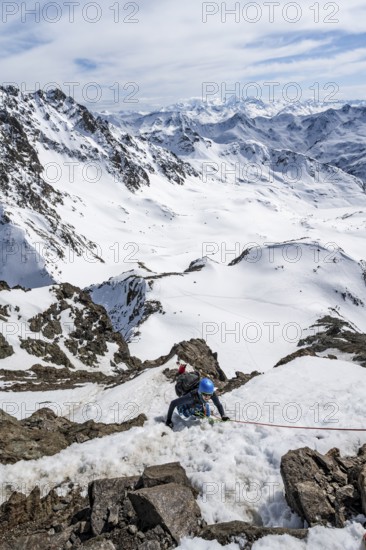 Mountaineer climbing up a steep snow slope, secured by a rope, ascent to the summit of Piz Grialetsch in winter, view of mountain panorama with snow, Grisons Haute Route, Albula Alps, Rhaetian Alps, Grisons, Switzerland