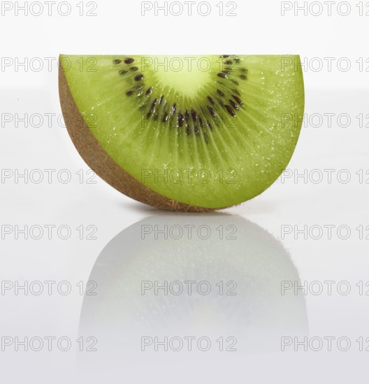 A kiwi slice, kiwi, kiwi fruit, Chinese gooseberry (Actinidia deliciosa) in front of a white background, studio photo